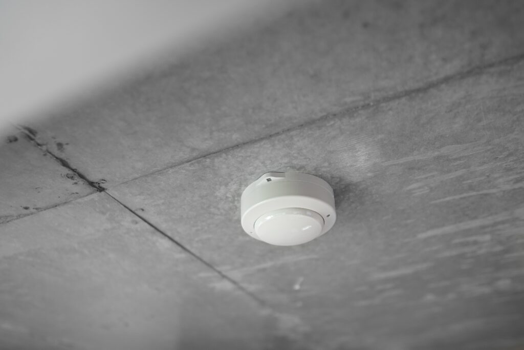 A white fire detector on a ceiling.